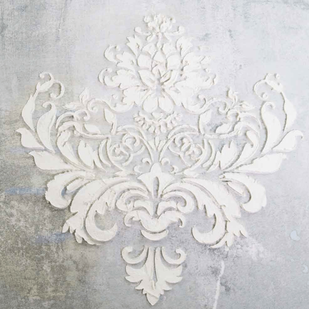 Decorative white stencil with intricate patterns on a textured gray background