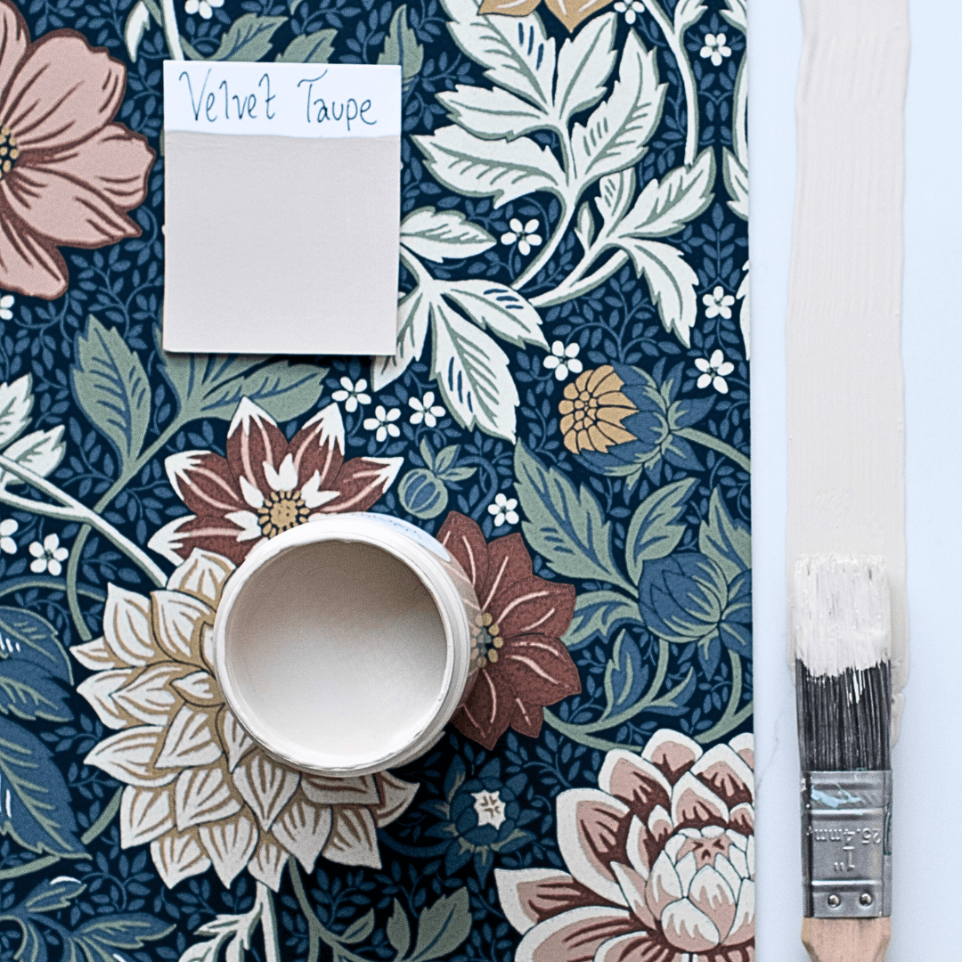 Floral wallpaper with a paintbrush and Velvet Taupe colour swatch on a blue background