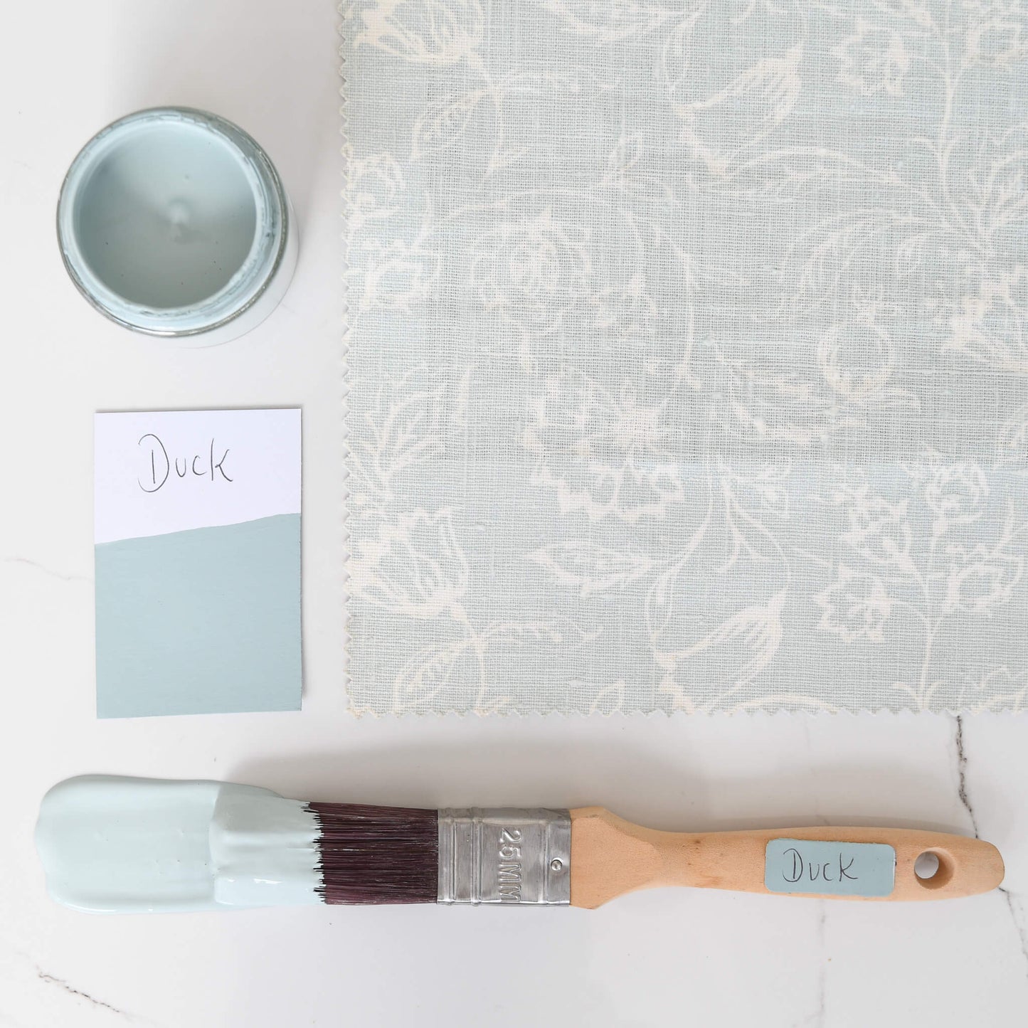 fabric mood board with paintbrush dipped in 120ml pot of Blake & Taylor Duck Chalk Furniture Paint