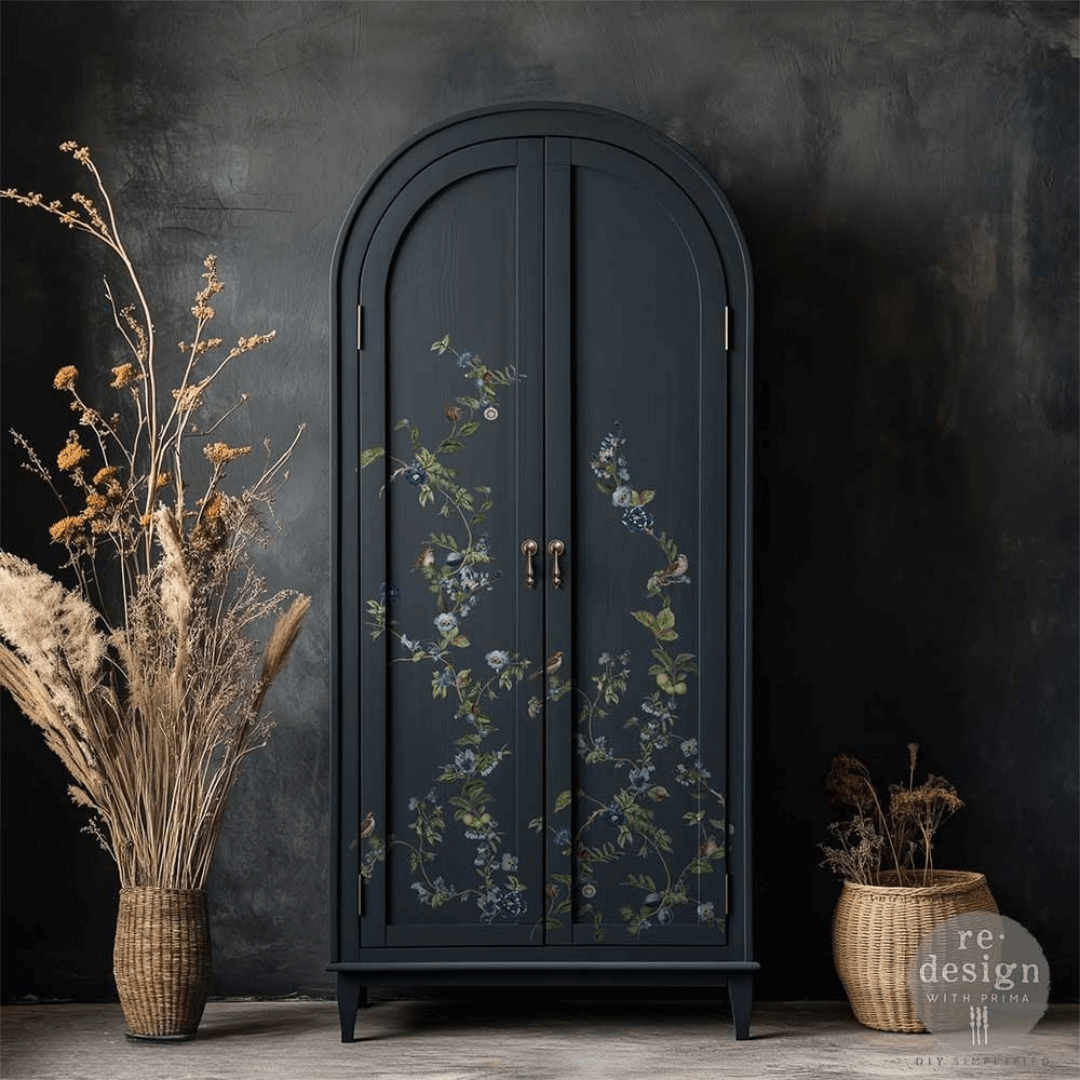 Dark blue armoire with floral patterns next to dried plants against a dark background