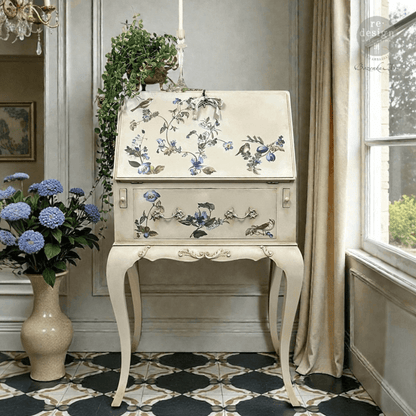 Decorative desk with floral patterns in a room with a vase of flowers and a window.