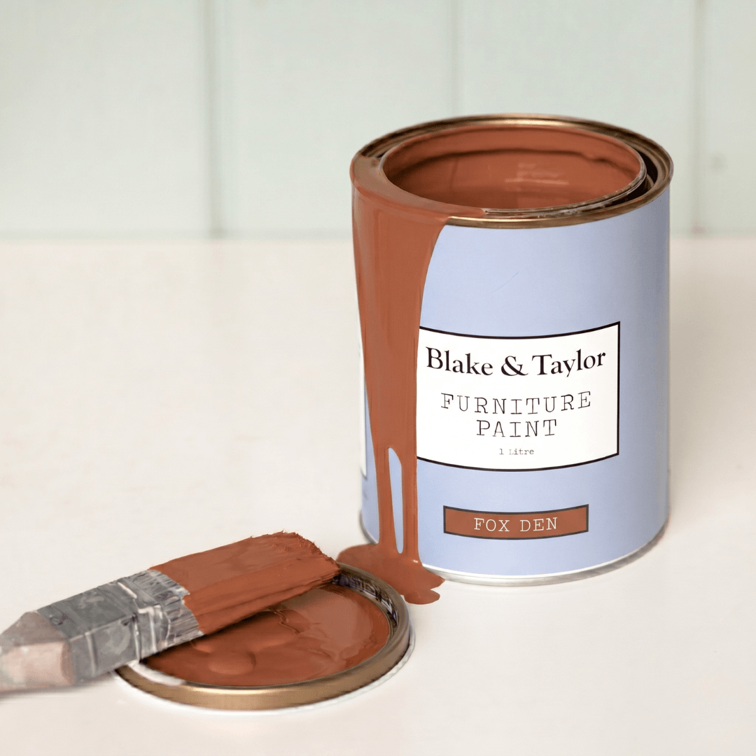 Can of Blake & Taylor Furniture Paint with a brush loaded with Fox Den paint on a light background