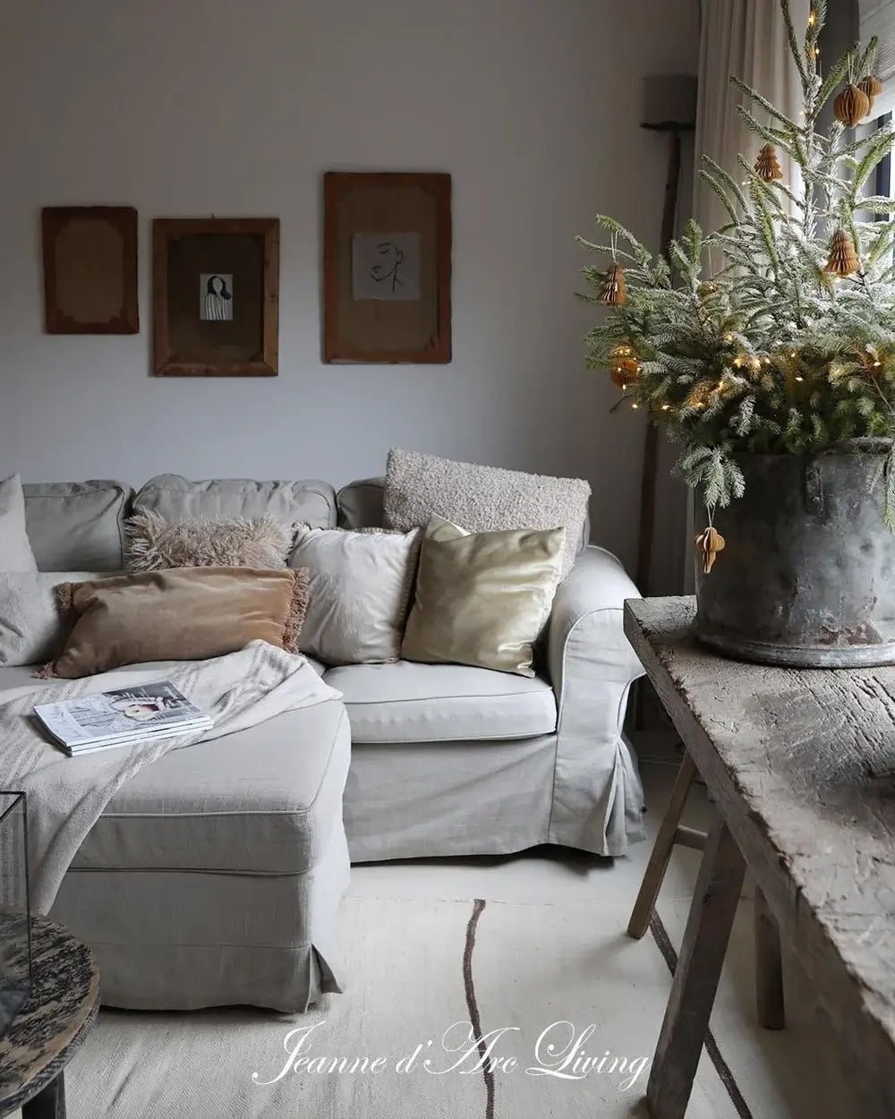 Cozy living room with a gray sectional sofa, decorative pillows, and a small Christmas tree.