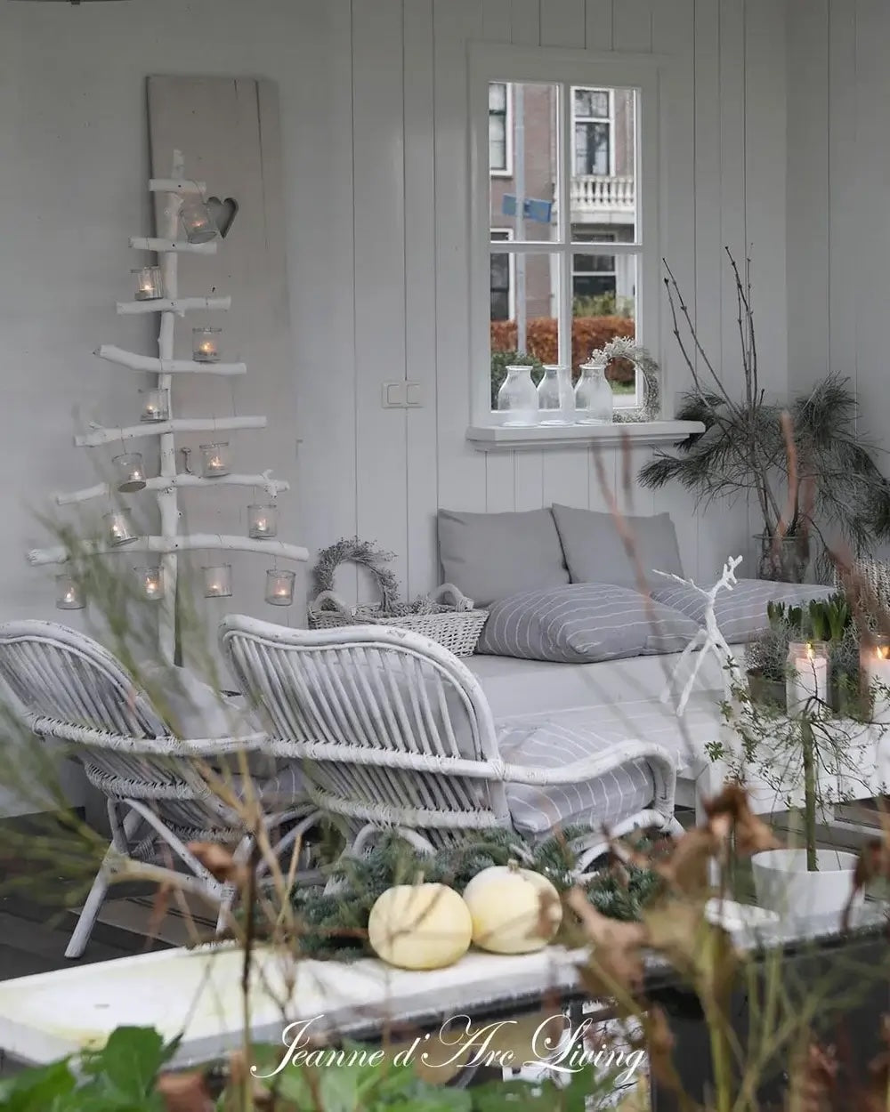 Cozy indoor setting with wicker furniture, candles, and decorative plants.