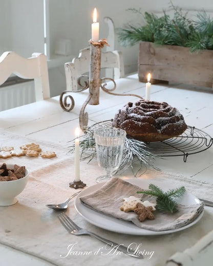 Dining table set with a cake, cookies, and candles in a cozy indoor setting.