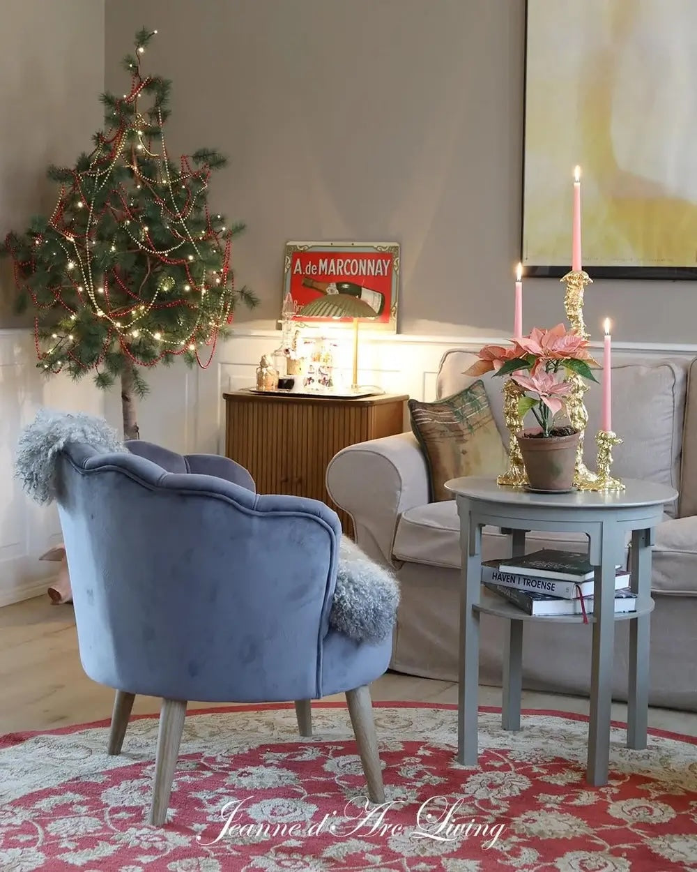 Cozy living room with a blue armchair, Christmas tree, and decorative table.