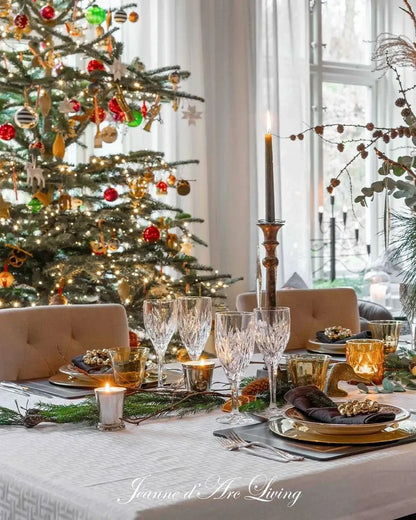 Decorated Christmas tree with a table set for dinner in a bright room.