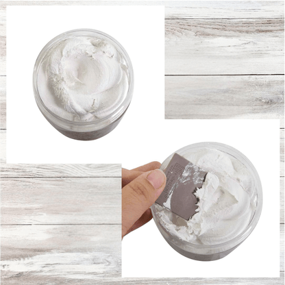 Jar of white cream with a hand holding a spatula, all on a wooden surface.