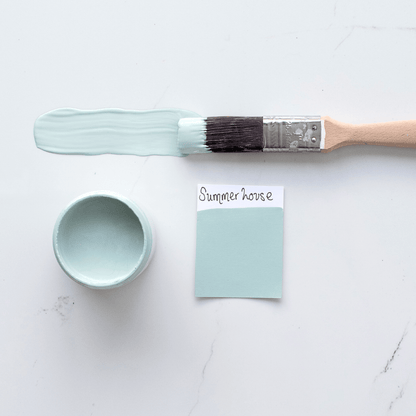 Paintbrush with a sample of 'Summerhouse' paint color next to a small container of the same paint on a light background.
