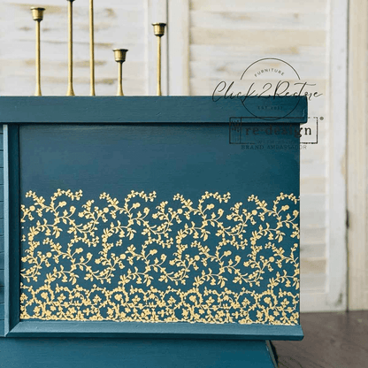 Teal decorative box with gold floral patterns against a neutral background