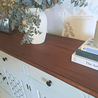 A close-up of wooden console cabinet painted Blake & taylor Paint, colour Willow with a dark brown wood top, styled with a white vase of eucalyptus and a stack of books. 