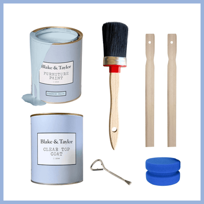 A furniture paint kit with two cans of Blake & Taylor furniture paint, a paint brush, two wooden sticks, a metal scraper, and two blue sanding discs, arranged on a white background with a blue border.