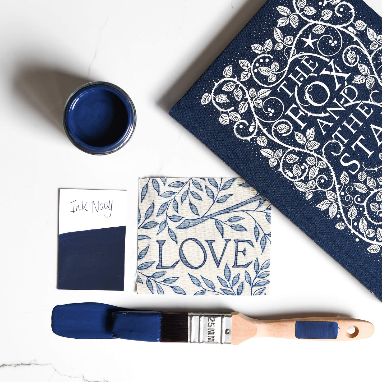 fabric mood board with paintbrush dipped in 120ml pot of Blake & Taylor Ink Navy Chalk Furniture Paint